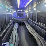 A spacious 26-passenger party bus with modern amenities, including vibrant interior lighting, comfortable seating, and a TV, shown ready for rental in Atlanta.