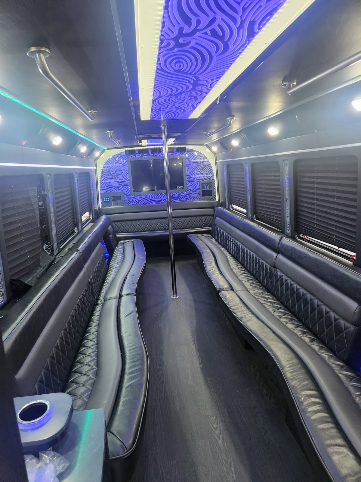 A spacious 26-passenger party bus with modern amenities, including vibrant interior lighting, comfortable seating, and a TV, shown ready for rental in Atlanta.