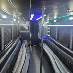 A luxurious 26-passenger party bus with LED lighting, plush seating, and a large TV, parked in a city setting near Atlanta, ready for rental