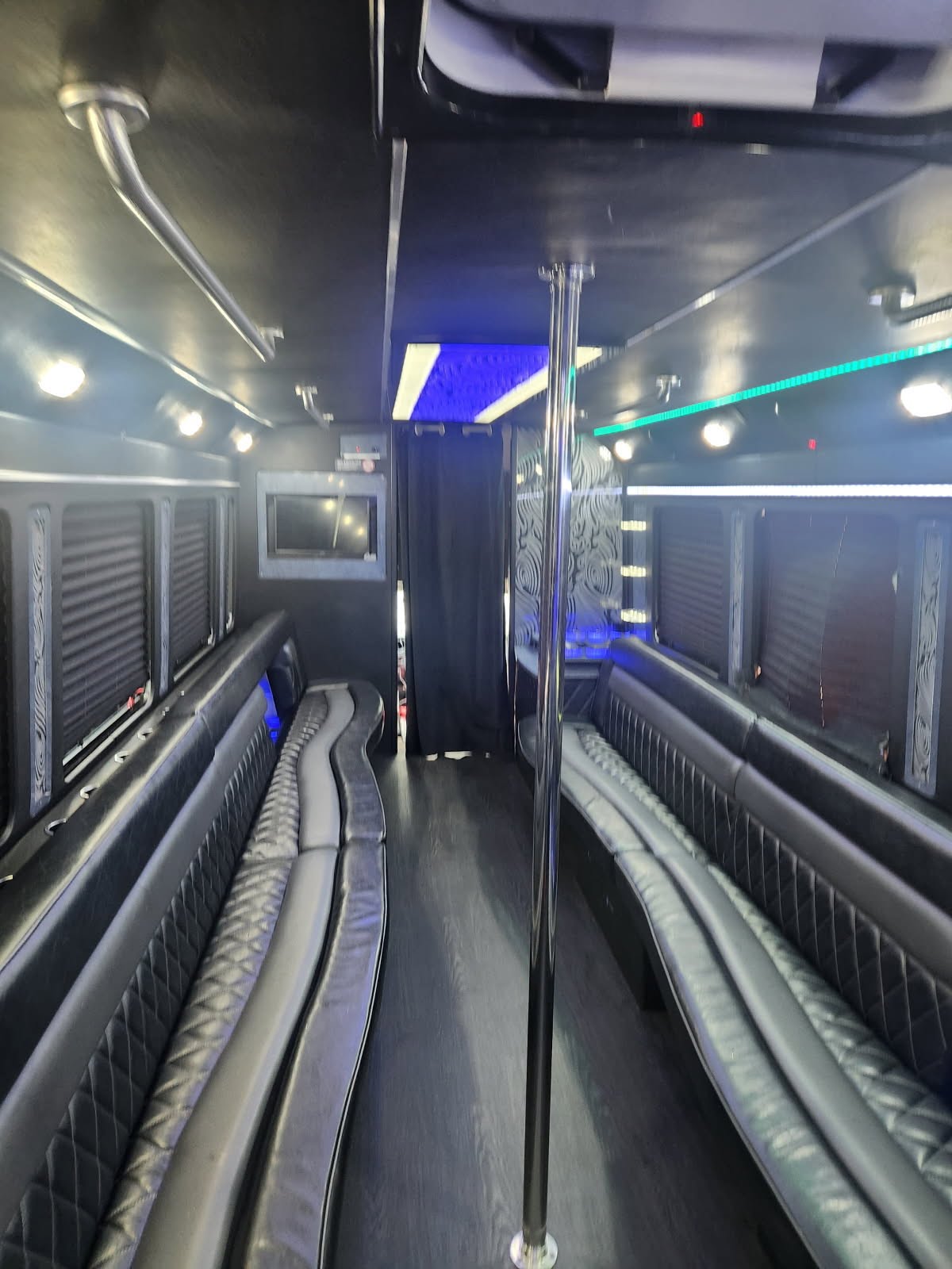 A luxurious 26-passenger party bus with LED lighting, plush seating, and a large TV, parked in a city setting near Atlanta, ready for rental