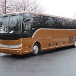 A side-view of a full-size, 56-passenger commercial coach bus with tinted windows and a clean, white exterior.